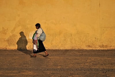 Wearing a white long sleeve shirt and black skirt woman standing in the wall yellow
